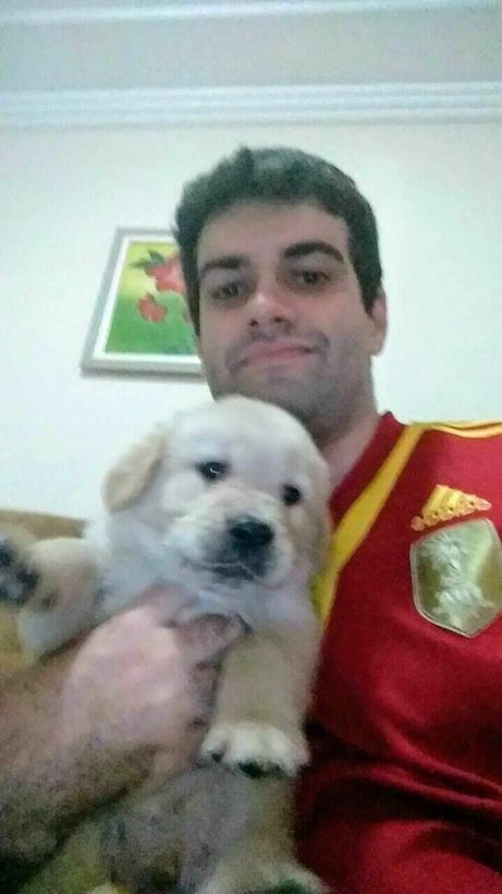 Anderson, de camisa vermelha, segura um filhote de golden retriever.
