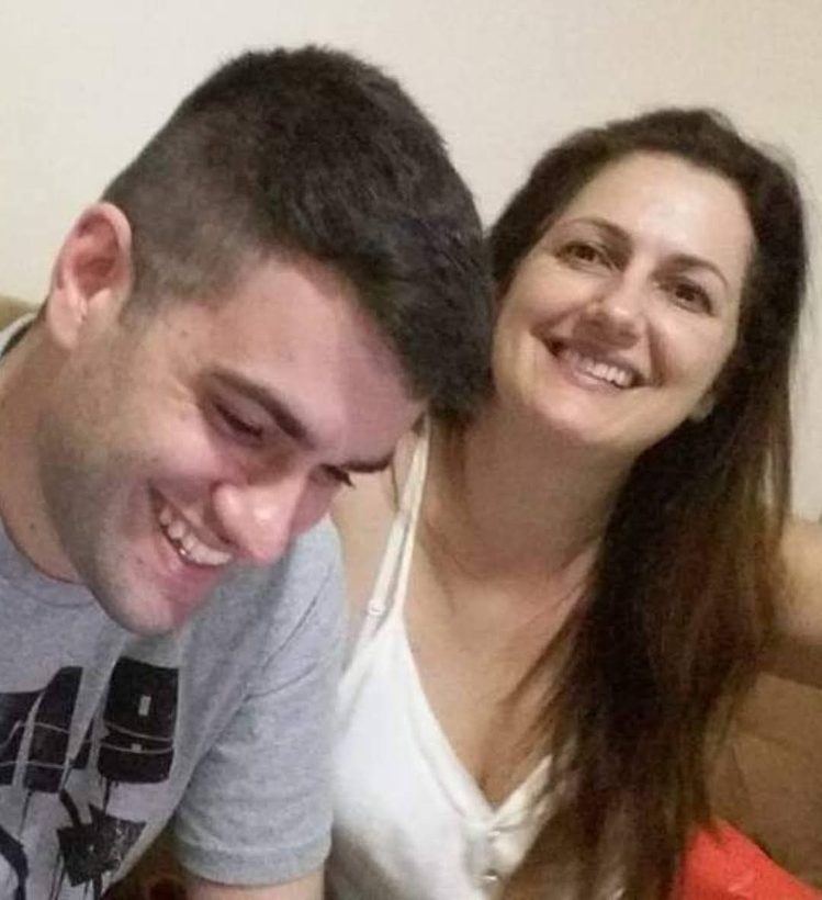 Anderson ri de olhos baixos ao lado da mãe, Verônica, que sorri para a câmera.